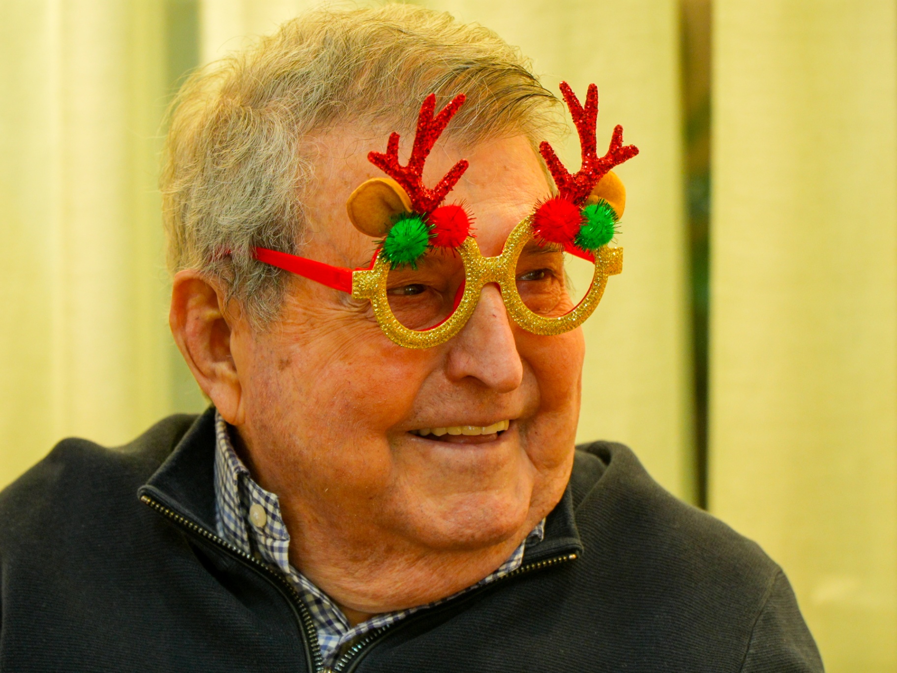 Persona mayor sonriendo con gafas navideñas